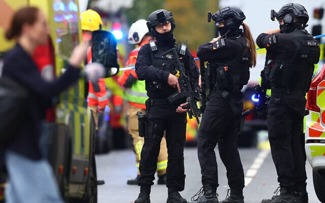 Armed police officers stand with their weapons outside Heaton Park Hebrew Congregation synagogue in Crumpsall, north Manchester, on October 2, 2025 (Paul Currie / AFP)