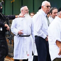 Rabbi Daniel Walker (3L) stands among armed police officers as they talk with members of the Jewish community outside Heaton Park Hebrew Congregation synagogue in Crumpsall, north Manchester, on October 2, 2025, following a deadly terrorist attack at the synagogue. (Paul Currie / AFP)
