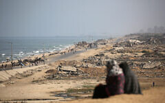 Palestinians walk on a coastal path northwest of Nuseirat refugee camp  on October 4, 2025. Israel said that its troops were still operating in Gaza City and warned residents not to return, despite halting an offensive to capture the city (Photo by Eyad BABA / AFP)