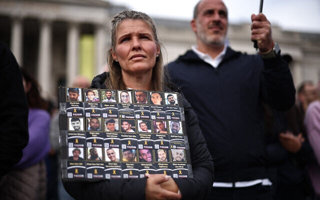 People hold photos of hostages as they gather for a commemorative event organized by the Jewish community to honor the lives lost in the Hamas massacre in southern Israel on October 7, 2023, in Trafalgar Square, London on October 5, 2025.  (Photo by HENRY NICHOLLS / AFP)