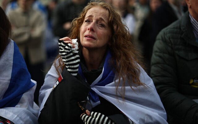 Tears are wiped away as people gather for a commemorative event organized by the Jewish community to honor the lives lost in the Hamas massacre in southern Israel on October 7, 2023, in Trafalgar Square, London on October 5, 2025.  (Photo by HENRY NICHOLLS / AFP)