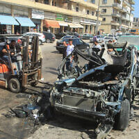 People gather around a destroyed car targeted in an Israeli drone attack in the southern Lebanese village of Zebdine, on October 6, 2025. (Mahmoud ZAYYAT / AFP)