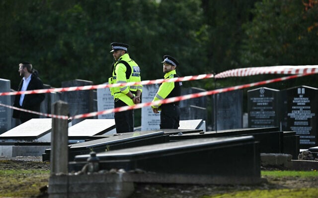 Police officers stand by graves at Agecroft Jewish Cemetery in Salford, northwest England, on October 6, 2025, during the funeral service of Adrian Daulby, one of two men killed in a terror attack on Heaton Park synagogue on October 2. (Paul Ellis/AFP) Police officers stand by graves at Agecroft Jewish Cemetery in Salford, northwest England, on October 6, 2025, during the funeral service of Adrian Daulby, one of two men killed in a terror attack on Heaton Park synagogue on October 2. (Paul Ellis/AFP)