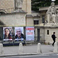 This photograph shows portrait placards of Cecile Kohler and Jacques Paris, two French citizens detained in Iran, set up on a fence of the French National Assembly, in Paris on October 6, 2025. (Photo by Martin LELIEVRE / AFP)