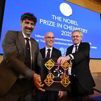 (L to R) Heiner Linke, Chair of the Nobel Committee for Chemistry, Hans Ellegren, Secretary General of The Royal Swedish Academy of Sciences, and Olof Ramstroem, Member of the Nobel Committe for Chemistry, pose with a model during a press conference to announce Japan's Susumu Kitagawa, UK-born Richard Robson and American-Jordanian Omar M. Yaghi as the winners of the 2025 Nobel Prize in Chemistry at the Royal Swedish Academy of Sciences in Stockholm, Sweden, on October 8, 2025. (Jonathan Nackstrand / AFP)