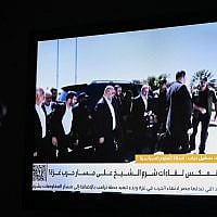 An Egyptian woman watches the news on a local channel in Cairo on October 8, 2025, showing images of top negotiator for the Palestinian Hamas movement Khalil al-Hayya (C) arriving in Sharm el-Sheikh for talks on ending the Gaza war.