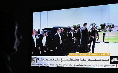 An Egyptian woman watches the news on a local channel in Cairo on October 8, 2025, showing images of top negotiator for the Palestinian Hamas movement Khalil al-Hayya (C) arriving in Sharm el-Sheikh for talks on ending the Gaza war.