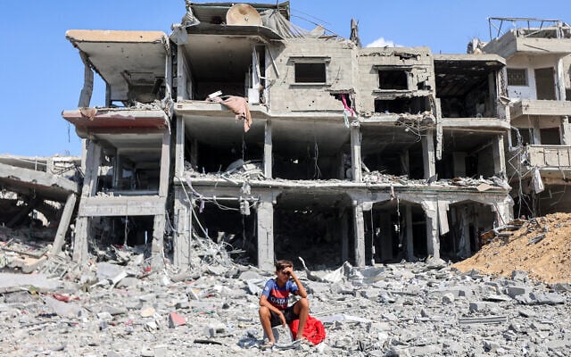 A boy sits amidst rubble outside a destroyed building in the center of Khan Younis in the southern Gaza Strip on October 10, 2025. (Omar AL-QATTAA / AFP)