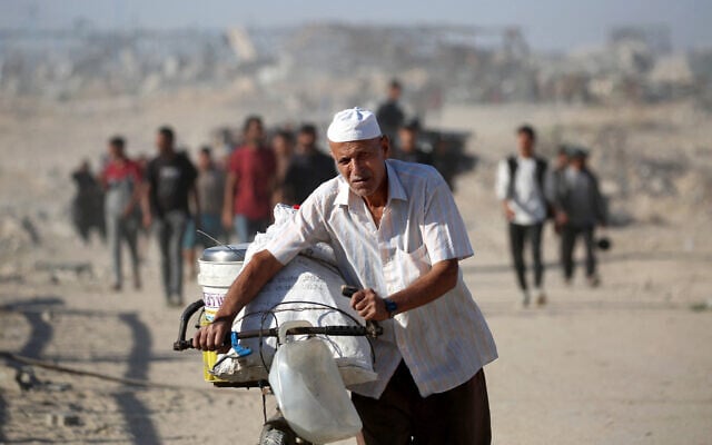 A Palestinian man pushes his bike as he and others make their way to Gaza City through the Netzarim corridor, from Nuseirat in the central Gaza Strip, on October 11, 2025. (Eyad BABA / AFP) A Palestinian man pushes his bike as he and others make their way to Gaza City through the Netzarim corridor, from Nuseirat in the central Gaza Strip, on October 11, 2025. (Eyad BABA / AFP)