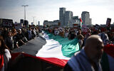 Anti-Israel protesters carry a large Palestinian flag through central London, on October 11, 2025. (Henry Nicholls/ AFP)