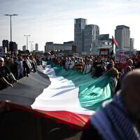Anti-Israel protesters carry a large Palestinian flag through central London, on October 11, 2025. (Henry Nicholls/ AFP)