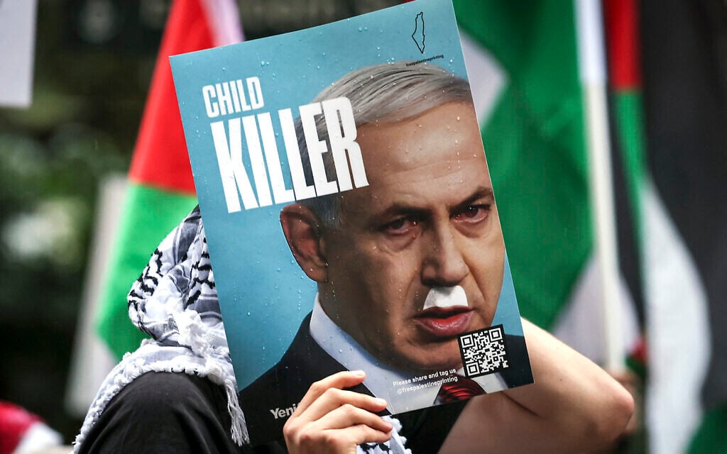 A demonstrator holds a placard showing Prime Minister Benjamin Netanyahu with a Hitler-style mustache and text that reads "child killer," during a rally in Sydney on October 12, 2025. (David Gray/ AFP) A demonstrator holds a placard showing Prime Minister Benjamin Netanyahu with a Hitler-style mustache and text that reads "child killer," during a rally in Sydney on October 12, 2025. (David Gray/ AFP)