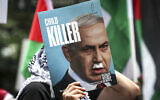 A demonstrator holds a placard showing Prime Minister Benjamin Netanyahu with a Hitler-style mustache and text that reads "child killer," during a rally in Sydney on October 12, 2025. (David Gray/ AFP)