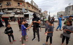 A member of the internal security forces loyal to Palestinian terror group Hamas greets young Gazans in the Nuseirat refugee camp in the central Gaza Strip, on October 12, 2025. (Eyad BABA / AFP)