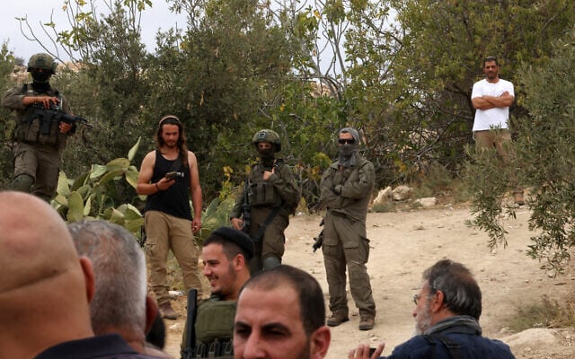 Illustrative: Israeli soldiers and settlers gather in the village of Edna, north of the West Bank city of Hebron, during the olive harvesting season, on October 12, 2025. (Photo by HAZEM BADER / AFP)