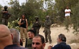 Illustrative: Israeli soldiers and settlers gather in the village of Edna, north of the West Bank city of Hebron, during the olive harvesting season, on October 12, 2025. (HAZEM BADER / AFP)