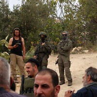 Illustrative: Israeli soldiers and settlers gather in the village of Edna, north of the West Bank city of Hebron, during the olive harvesting season, on October 12, 2025. (HAZEM BADER / AFP)