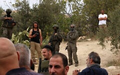 Illustrative: Israeli soldiers and settlers gather in the village of Edna, north of the West Bank city of Hebron, during the olive harvesting season, on October 12, 2025. (HAZEM BADER / AFP)