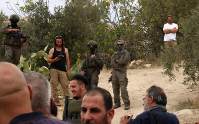 Illustrative: Israeli soldiers and settlers gather in the village of Edna, north of the West Bank city of Hebron, during the olive harvesting season, on October 12, 2025. (HAZEM BADER / AFP)