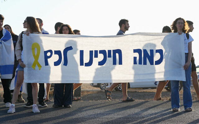 Israelis gather to show support for hostages about to arrive in the Reim military base in southern Israel from Gaza on October 13, 2025. Hebrew writing on banner reads: 'How much we've been waiting for you' (MAYA LEVIN / AFP)
