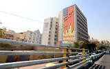 Commuteres drive past a building with an anti-US mural with the slogan "Down with the USA" and skulls replacing the stars on the flag, in Tehran on October 13, 2025. (ATTA KENARE / AFP)