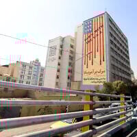 Commuteres drive past a building with an anti-US mural with the slogan "Down with the USA" and skulls replacing the stars on the flag, in Tehran on October 13, 2025. (ATTA KENARE / AFP)