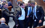 Knesset member Ayman Odeh (C) is escorted out after holding a sign reading "Recognize Palestine" during a speech by US President Donald Trump at the Knesset, in Jerusalem on October 13, 2025.  (Photo by Evan Vucci / POOL / AFP)