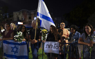 People carry flowers and Israeli flags upon the arrival of vehicles transporting the bodies of four hostages, in front of the National Center for Forensic Medicine in Tel Aviv on October 13, 2025. The Hebrew sign reads, "Sorry." (Jalaa MAREY / AFP) People carry flowers and Israeli flags upon the arrival of vehicles transporting the bodies of four hostages, in front of the National Center for Forensic Medicine in Tel Aviv on October 13, 2025. The Hebrew sign reads, "Sorry." (Jalaa MAREY / AFP)