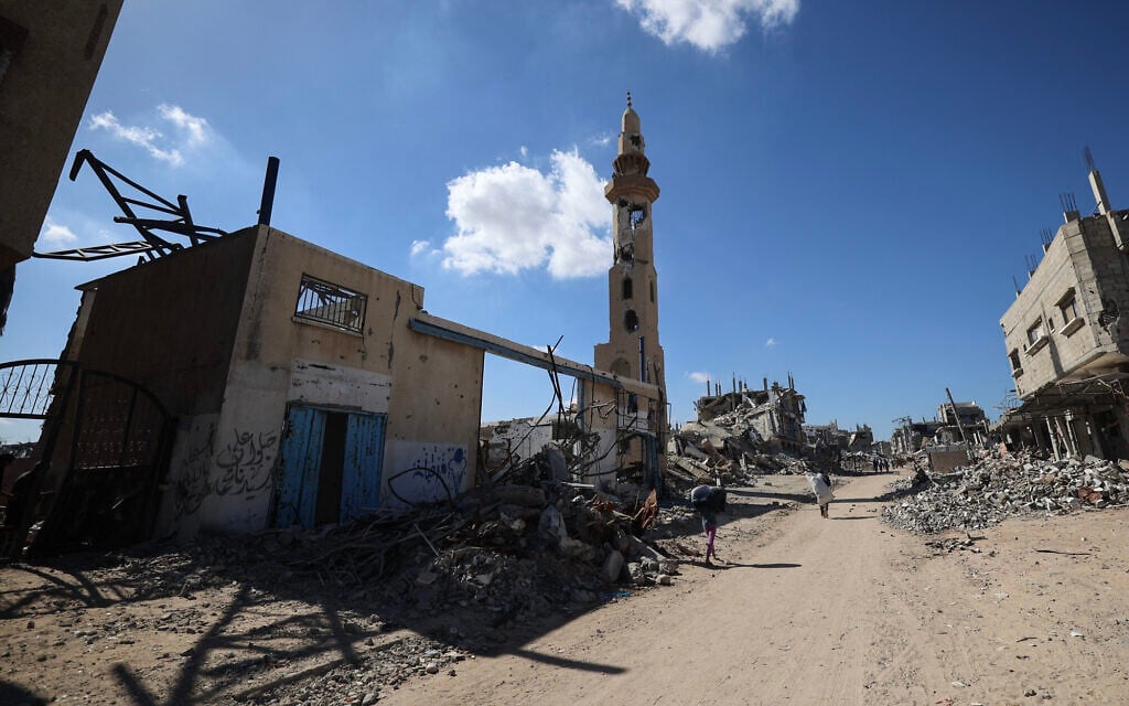 Palestinians walk past destroyed buildings as displaced residents return to their homes in the in al-Zahra area, north of the Nuseirat refugee camp, in the central Gaza Strip, on October 14, 2025. (Eyad BABA / AFP)