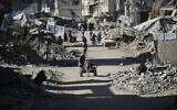 A man rides a donkey cart past destroyed buildings as displaced Palestinians return to their homes in the in al-Zahra area, north of the Nuseirat refugee camp in the central Gaza Strip, on October 14, 2025, amid the Gaza ceasefire brokered by US President Donald Trump. (Eyad BABA / AFP)