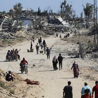 Displaced Palestinians walk past destroyed buildings as they return to their homes in the in al-Zahra area, north of the Nuseirat refugee camp in the central Gaza Strip, on October 14, 2025. (Eyad BABA / AFP)