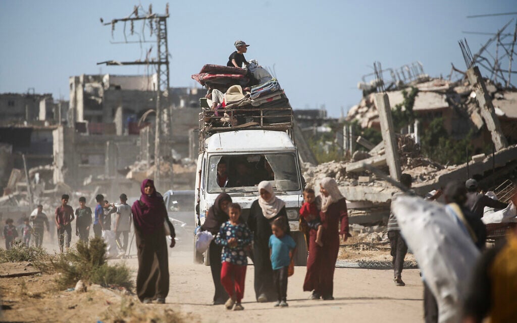 A child sits on top of a vehicle loaded with belongings as displaced Palestinians return to their homes in the in al-Zahra area, north of the Nuseirat refugee camp in the central Gaza Strip, on October 14, 2025 (Eyad BABA / AFP)