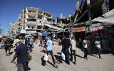Palestinians walk past a destroyed building at a makeshift market in the Nuseirat refugee camp, located in the central Gaza Strip, on October 15, 2025. (Eyad BABA / AFP)