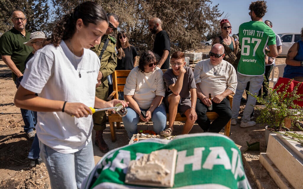 Members of the Kfar Aza kibbutz mourn in front of the grave of a victim as they hold a memorial service for those killed in Hamas's October 7, 2023 attack on Israel, in Kibbutz Kfar Aza on October 16, 2025. (Maya Levin / AFP)