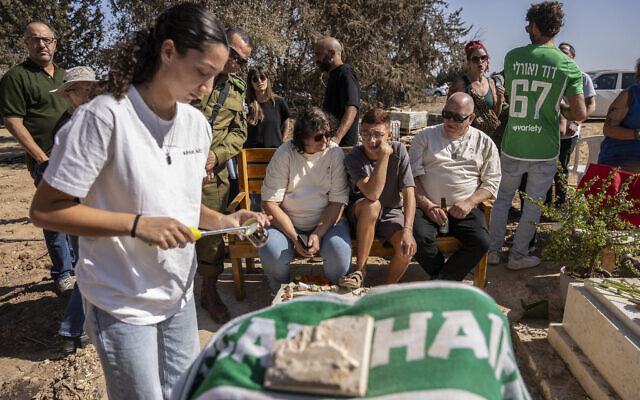 Members of the Kfar Aza kibbutz mourn in front of the grave of a victim as they hold a memorial service for those killed in Hamas's October 7, 2023 attack on Israel, in Kibbutz Kfar Aza on October 16, 2025. (Maya Levin / AFP)