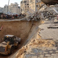 People and members of the International Committee of the Red Cross (ICRC) watch as Palestinians use an excavator to dig deep into the ground, reportedly searching for bodies of hostages, in Khan Younis in the southern Gaza Strip on October 17, 2025 (Omar AL-QATTAA / AFP)