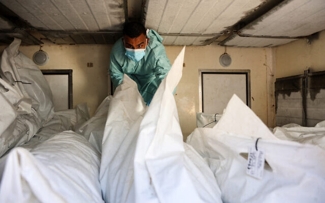 A hospital employee checks the remains of Palestinians released by Israel under a Gaza ceasefire and hostage exchange deal, inside a truck in front of the Nasser hospital in Khan Younis in the southern Gaza Strip, October 18, 2025. (Omar AL-QATTAA / AFP)