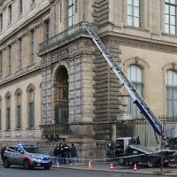 French police officers stand next to a basket lift used by robbers to enter the Louvre Museum, on Quai Francois Mitterrand, in Paris on October 19, 2025. (Dimitar DILKOFF / AFP)