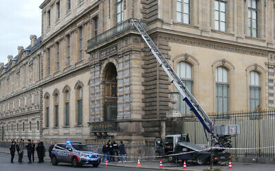 French police officers stand next to a basket lift used by robbers to enter the Louvre Museum, on Quai Francois Mitterrand, in Paris on October 19, 2025. (Dimitar DILKOFF / AFP)