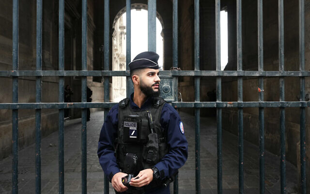 A French police officer stands in front of the Louvre Museum after a robbery, in Paris on October 19, 2025. (Dimitar DILKOFF / AFP)