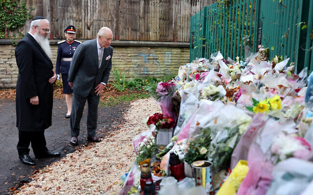 Britain's King Charles III looks at bouquets of flowers during a visit to Heaton Park Hebrew Congregation synagogue in Crumpsall, north Manchester, on October 20, 2025. On October 2, 2025, an attacker drove a car into a crowd outside the synagogue before going on a stabbing spree, killing two people and leaving three wounded. (Photo by Chris Jackson / POOL / AFP)