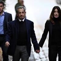 France's former president Nicolas Sarkozy (C), with his wife Carla Bruni-Sarkozy, leaves his residence to present himself to La Sante Prison for incarceration on a five-year prison sentence, on October 21, 2025. (JULIEN DE ROSA / AFP)
