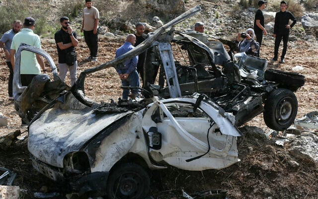 People inspect the wreckage of a vehicle targeted by an alleged Israeli strike in the southern Lebanese village of Harouf on October 25, 2025. (MAHMOUD ZAYYAT / AFP)