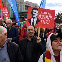 A protester holds a banner with the pictures of jailed Istanbul Mayor Ekrem Imamoglu during a rally organized by the country's main opposition party, the Republican People's Party (CHP), to protest the suspension and imprisonment of Istanbul Mayor, in Istanbul on October 26, 2025. (Yasin AKGUL / AFP)