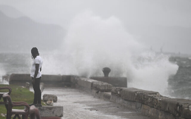 A man watches the waves crash into the walls at the Kingston Waterfront on October 27, 2025 (Ricardo Makyn / AFP)