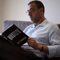 Eli Sharabi, who was abducted during the Hamas cross-border attack on Israel on October 7, 2023, and held hostage by Hamas for 16 months, poses with his new book "Hostage" for a photo in Herzliya, on September 18, 2025. (AP Photo/Ariel Schalit)