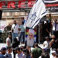 A man waves an Israeli flag over a picture of Sheikh Muafak Tarif, the spiritual leader of the Druze in Israel, during a weekly rally in Sweida, southern Syria, on September 20, 2025. (AP Photo/Fahd Kiwan)