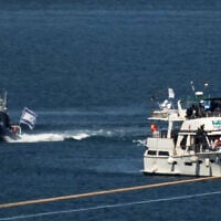Activists in orange life jackets sit aboard a Gaza-bound Sumud flotilla boat as Israeli navy soldiers sail it into the port of Ashdod, Israel, October 2, 2025, after it was intercepted while approaching the Gaza coast. (AP Photo/Leo Correa)