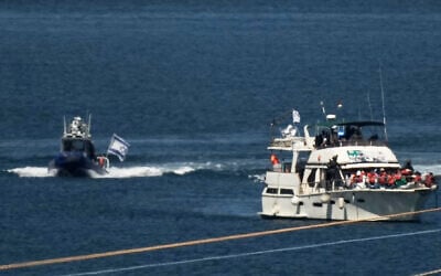 Activists in orange life jackets sit aboard a Gaza-bound Sumud flotilla boat as Israeli navy soldiers sail it into the port of Ashdod, Israel, October 2, 2025, after it was intercepted while approaching the Gaza coast. (AP Photo/Leo Correa)