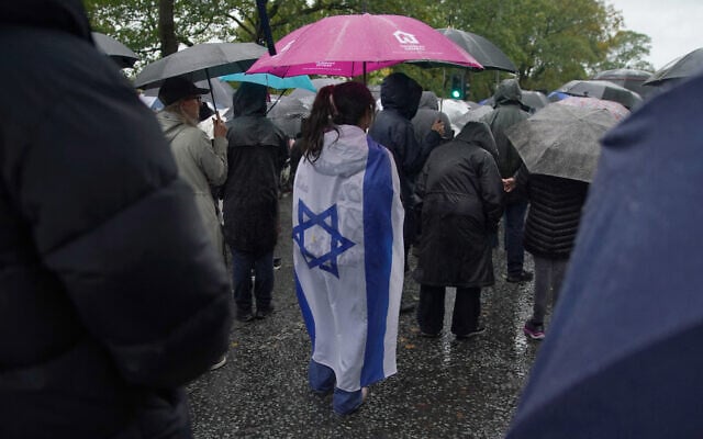 A woman wears an Israeli flag wrapped over her back as she attends a vigil for the victims of the Yom Kippur terrorist attack on the Heaton Park Hebrew Congregation synagogue in Crumpsall, Manchester, England, October 3, 2025. (AP Photo/Ian Hodgson)